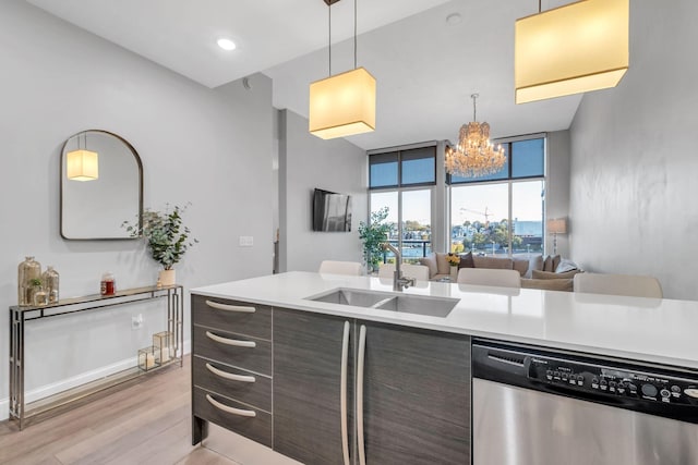 kitchen featuring sink, decorative light fixtures, dark brown cabinets, light wood-type flooring, and stainless steel dishwasher