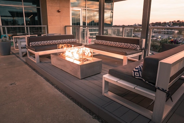 deck at dusk with an outdoor living space with a fire pit