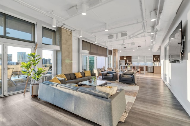 living room featuring a towering ceiling, wood-type flooring, and track lighting