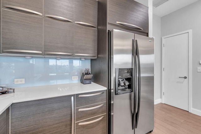 kitchen with dark brown cabinets, light wood-type flooring, and stainless steel refrigerator with ice dispenser