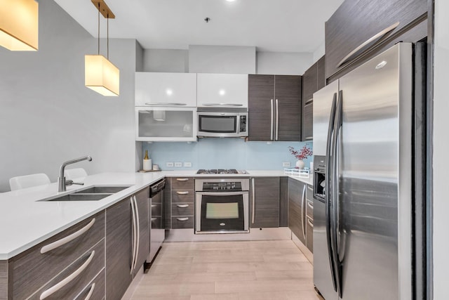 kitchen with pendant lighting, sink, light hardwood / wood-style flooring, white cabinetry, and stainless steel appliances