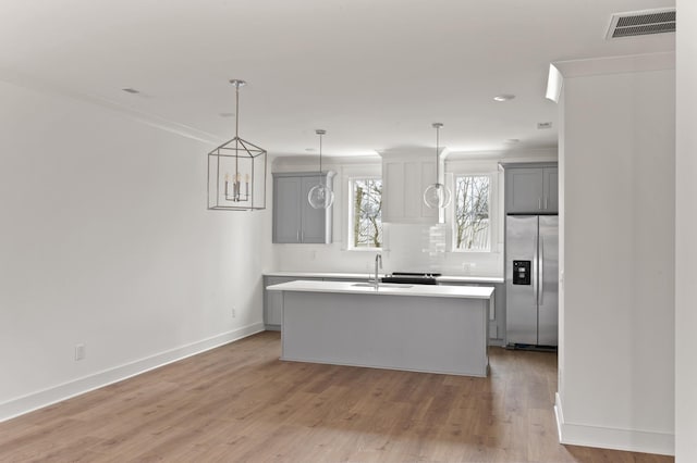 kitchen featuring a kitchen island, decorative light fixtures, gray cabinetry, stainless steel fridge with ice dispenser, and light wood-type flooring