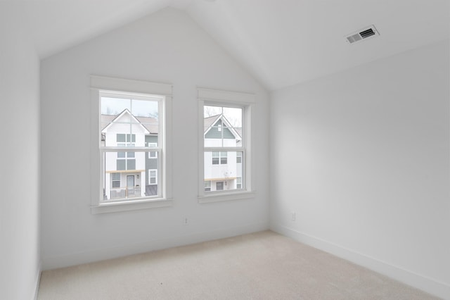 carpeted spare room featuring vaulted ceiling