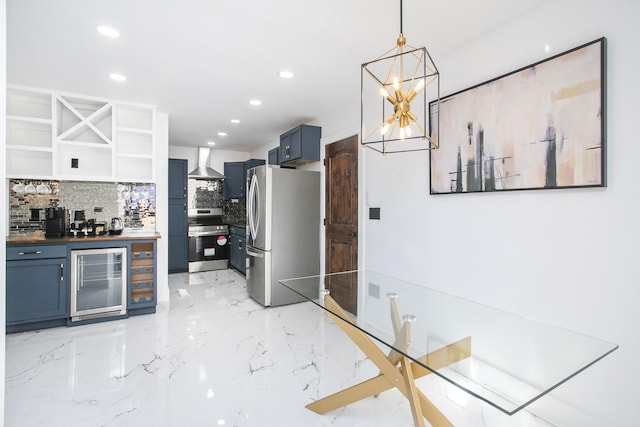 kitchen with blue cabinetry, hanging light fixtures, stainless steel appliances, wine cooler, and wall chimney exhaust hood