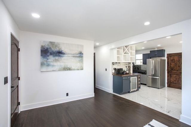 kitchen with appliances with stainless steel finishes, tasteful backsplash, beverage cooler, blue cabinetry, and light wood-type flooring