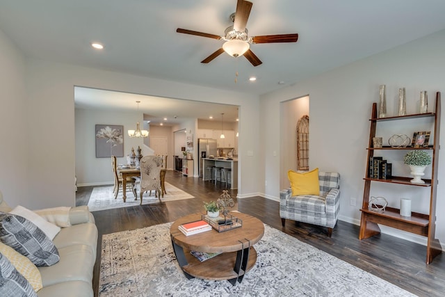 living room featuring dark hardwood / wood-style floors and ceiling fan with notable chandelier