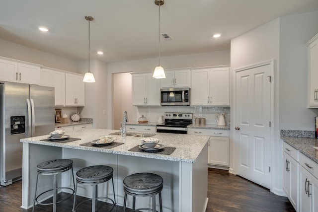 kitchen featuring pendant lighting, sink, appliances with stainless steel finishes, light stone countertops, and white cabinets