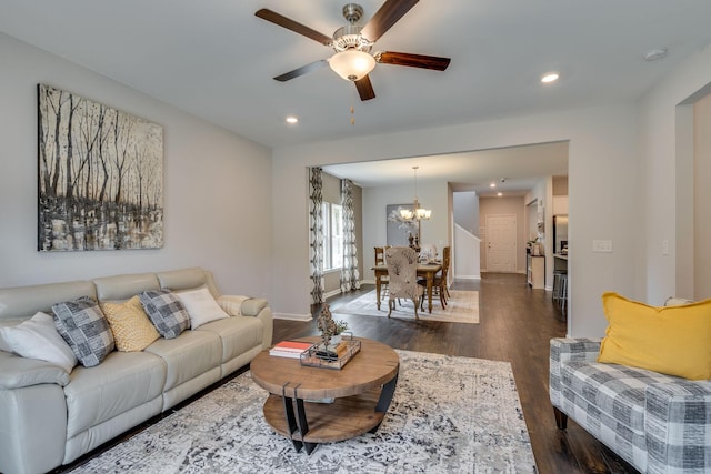 living room featuring ceiling fan with notable chandelier and dark hardwood / wood-style floors