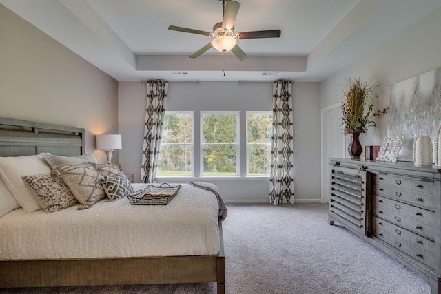 carpeted bedroom featuring a tray ceiling and ceiling fan