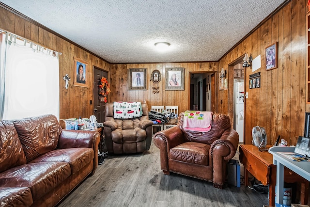 living room with hardwood / wood-style floors, crown molding, wooden walls, and a textured ceiling