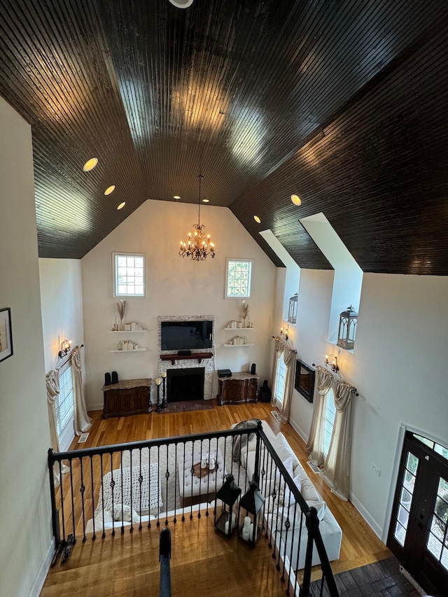 interior space with an inviting chandelier, hardwood / wood-style flooring, a wealth of natural light, and vaulted ceiling