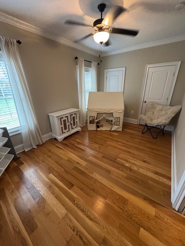 interior space featuring crown molding, ceiling fan, wood-type flooring, and a textured ceiling