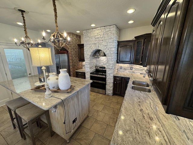 kitchen featuring sink, a center island, dark brown cabinetry, light stone countertops, and stainless steel range with electric cooktop