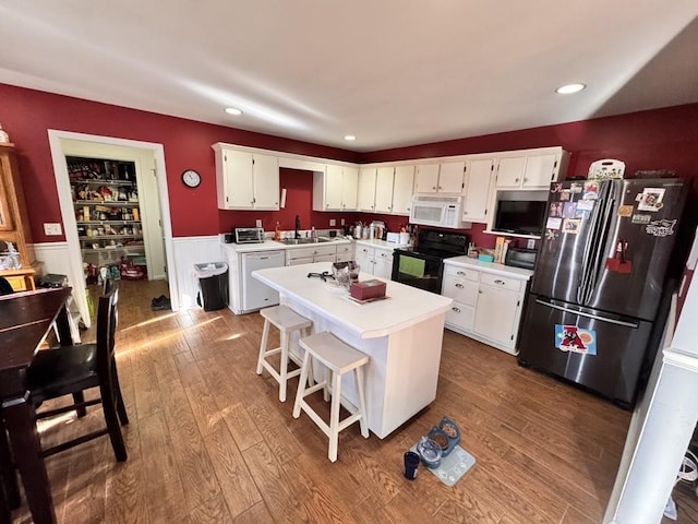 kitchen with a kitchen island, white cabinetry, black electric range oven, sink, and stainless steel fridge