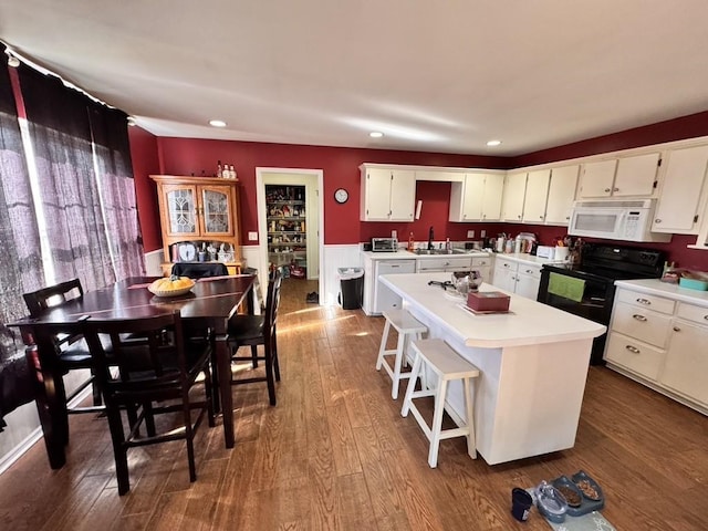 kitchen featuring a kitchen island, dark hardwood / wood-style floors, white cabinetry, sink, and electric range