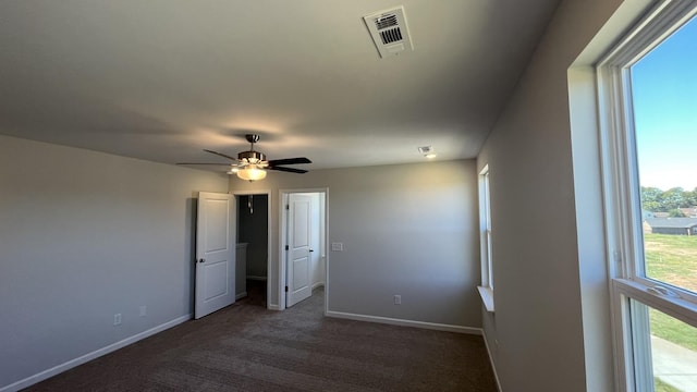 spare room with dark colored carpet and ceiling fan