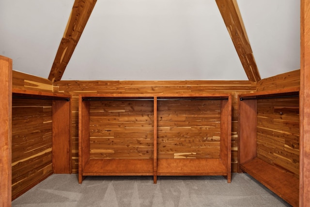 interior space with lofted ceiling with beams, carpet, and wood walls