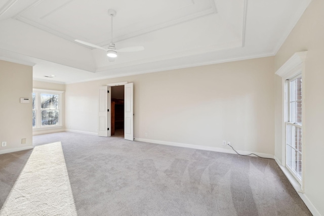 carpeted empty room with crown molding, a wealth of natural light, a raised ceiling, and ceiling fan