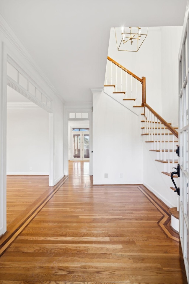 entrance foyer with hardwood / wood-style floors, ornamental molding, french doors, and a chandelier