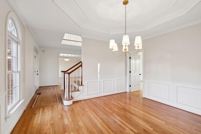 interior space featuring crown molding, a tray ceiling, light hardwood / wood-style floors, and a notable chandelier