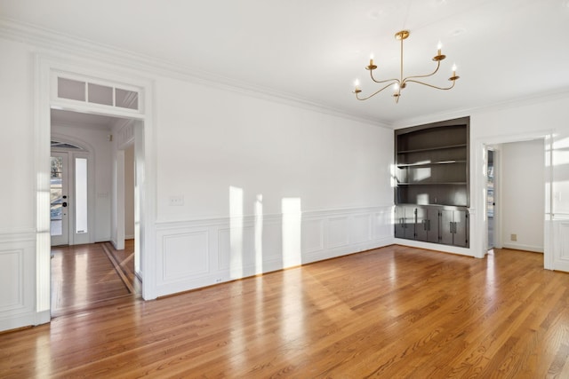 interior space featuring an inviting chandelier, ornamental molding, and hardwood / wood-style floors