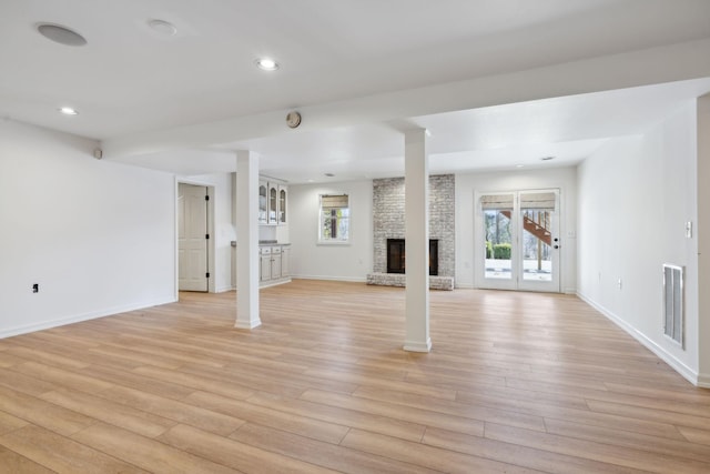 unfurnished living room featuring a wealth of natural light, a fireplace, and light wood-type flooring