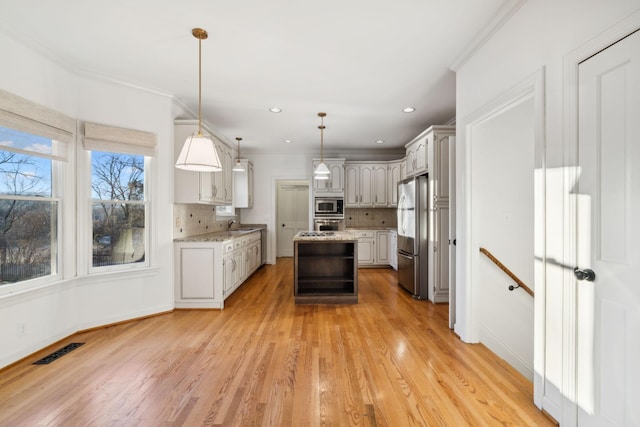 kitchen with pendant lighting, decorative backsplash, appliances with stainless steel finishes, and a kitchen island