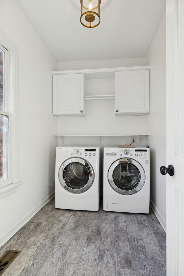 washroom with washer and dryer, hardwood / wood-style floors, and cabinets