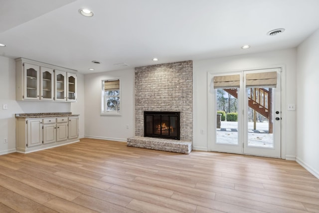 unfurnished living room with a brick fireplace and light hardwood / wood-style floors