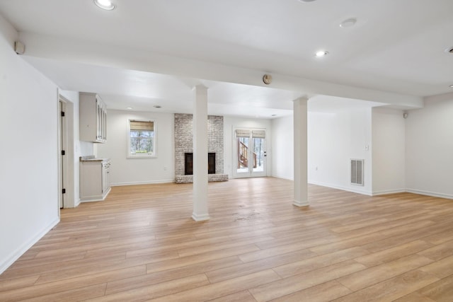 unfurnished living room with decorative columns, a fireplace, and light hardwood / wood-style flooring