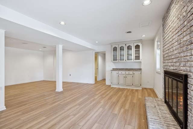 unfurnished living room with light hardwood / wood-style floors and a brick fireplace