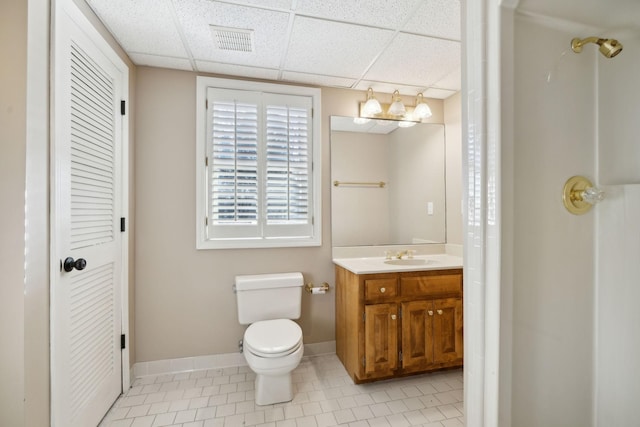 bathroom with a drop ceiling, vanity, tile patterned flooring, and toilet