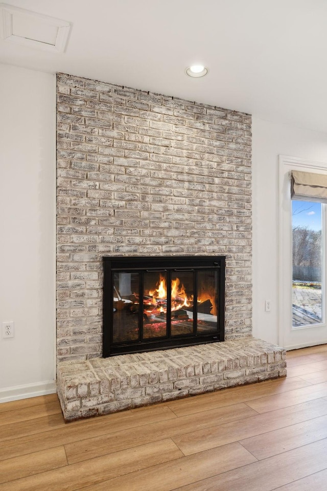 room details featuring a brick fireplace and wood-type flooring