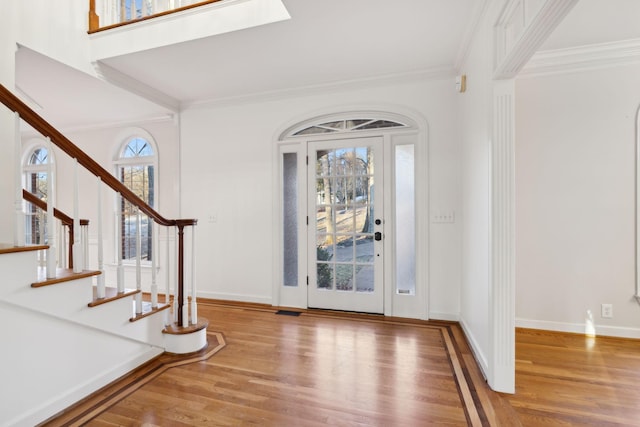 foyer with crown molding, light hardwood / wood-style floors, and a skylight