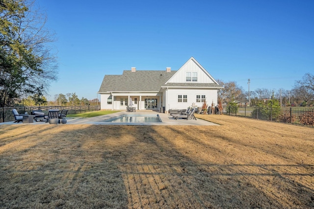 back of house with a fenced in pool, a lawn, and a patio area