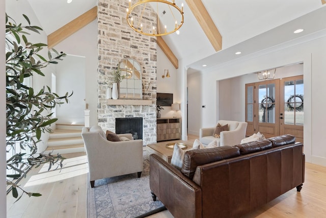 living room with a stone fireplace, a chandelier, beam ceiling, and light wood-type flooring