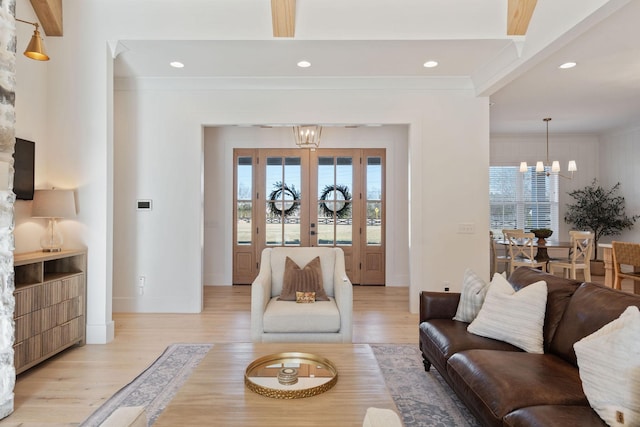 living room featuring crown molding, a notable chandelier, and light wood-type flooring