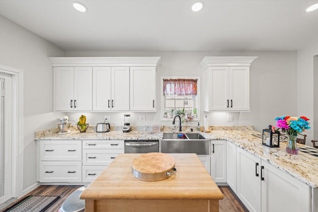 kitchen with sink, dark hardwood / wood-style flooring, dishwasher, light stone countertops, and white cabinets