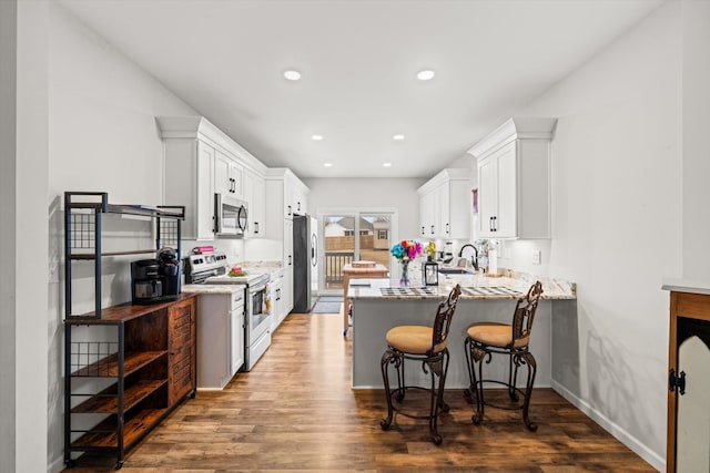 kitchen featuring dark wood-type flooring, stainless steel appliances, kitchen peninsula, and white cabinets