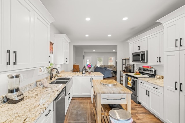 kitchen featuring stainless steel appliances, white cabinetry, wood-type flooring, and light stone counters