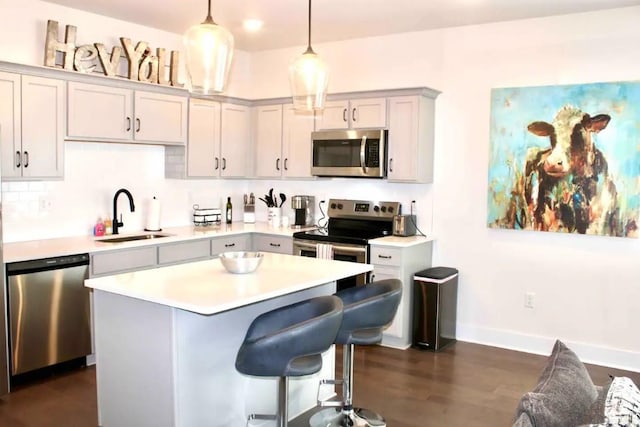 kitchen featuring sink, decorative light fixtures, a center island, appliances with stainless steel finishes, and gray cabinets