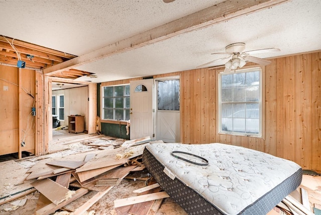 miscellaneous room featuring ceiling fan, wooden walls, and a textured ceiling