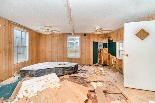 interior space with wooden walls, a textured ceiling, and ceiling fan