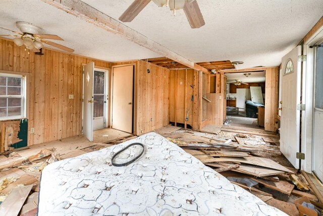 misc room featuring ceiling fan and wooden walls