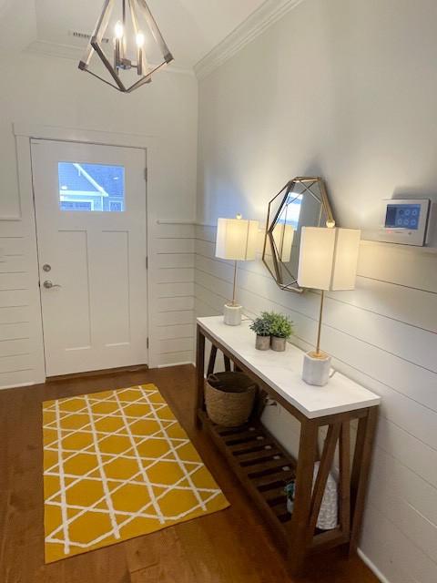 foyer featuring a notable chandelier, crown molding, and dark hardwood / wood-style floors