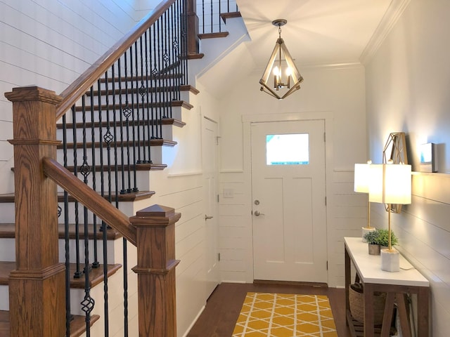 foyer entrance with ornamental molding, dark hardwood / wood-style floors, and an inviting chandelier