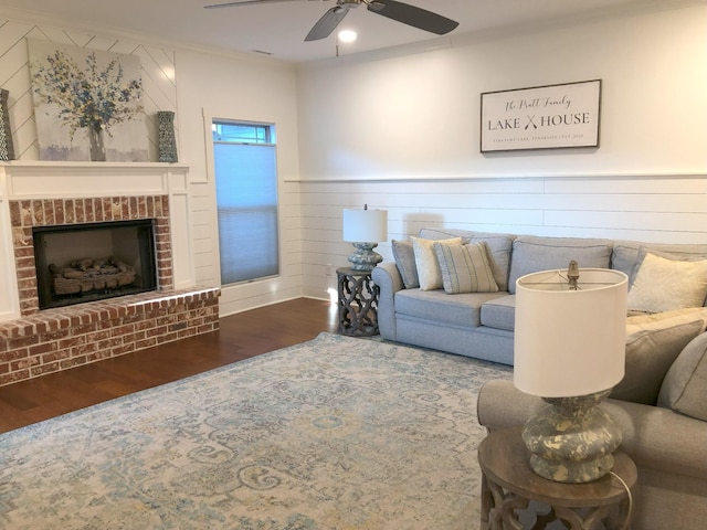 living room with crown molding, ceiling fan, a fireplace, and hardwood / wood-style flooring