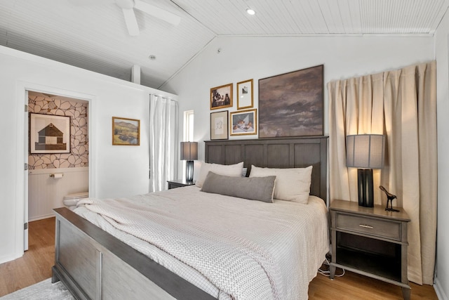 bedroom with ceiling fan, lofted ceiling, ensuite bathroom, and light hardwood / wood-style floors