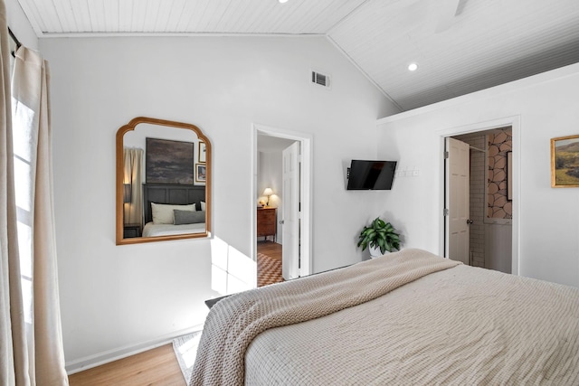 bedroom featuring ensuite bath, a spacious closet, vaulted ceiling, and light hardwood / wood-style flooring