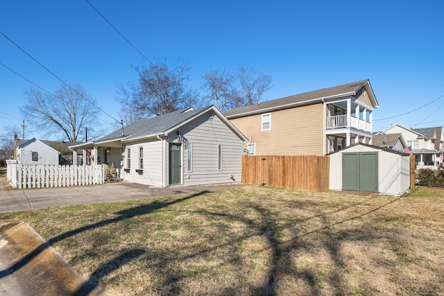 view of side of property with a shed, a lawn, a balcony, and a patio area